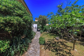 A stone pathway leading to a building with a white facade and a small statue at the entrance.