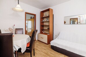 Um quarto com uma mesa de jantar, cadeiras, um sofá, um armário de madeira e um espelho na parede.