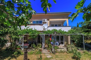 A two-story house with a garden, a satellite dish, and a covered patio area.