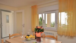 A dining table with a bowl of fruit, a glass of wine, and a vase of flowers. - Apartment Visnja (Rijeka)