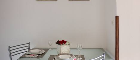 A dining table set with plates, cutlery, and a vase with flowers.
