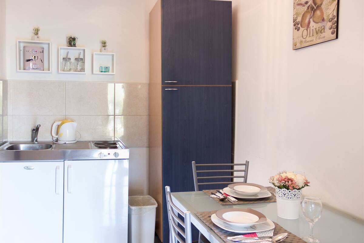 A compact kitchen with a refrigerator, sink, and a dining area with a table set for two.