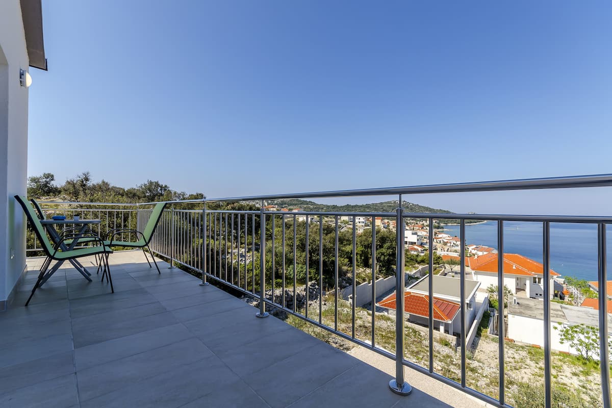 A balcony with a metal railing, a table, and two chairs.