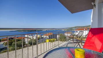 Ein Balkon mit Blick auf das Meer, ein Tisch mit Glasplatte und ein gelbes Kerzenlicht.