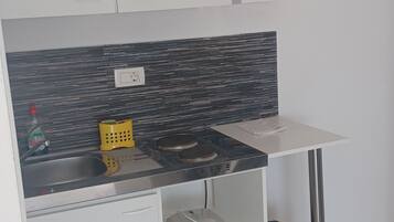 Eine kompakte Küche mit modernem Design, inklusive schwarzer Spritzschutzwand, eingebautem Herd und Spüle.