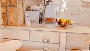 A dining table with a bottle and two glasses, a vase with dried plants, and a fruit bowl on the counter. - Apartments Mila (Ubli)