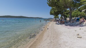 A beach with clear water, people sunbathing, and a distant hill. - House Marina (Zaboric)