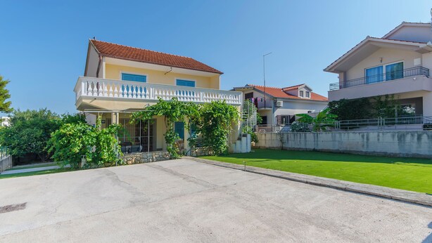 A two-story house with a balcony, a well-maintained lawn, and a clear sky. - House Marina (Zaboric)