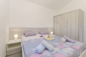 A neatly made bed with a patterned bedspread, a bedside table with a lamp, and a wardrobe.