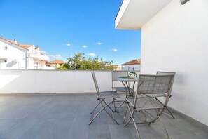 A rooftop terrace with a table and chairs, a potted plant, and a view of buildings in the distance. - Apartments Endless Summer (Srima)