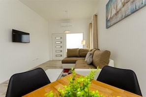 Una sala de estar moderna con un sofá, una mesa de centro y un televisor montado en la pared.