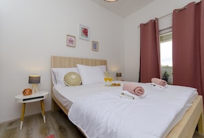 Una cama doble con ropa de cama blanca, una mesita de noche con lámpara y un adorno decorativo.