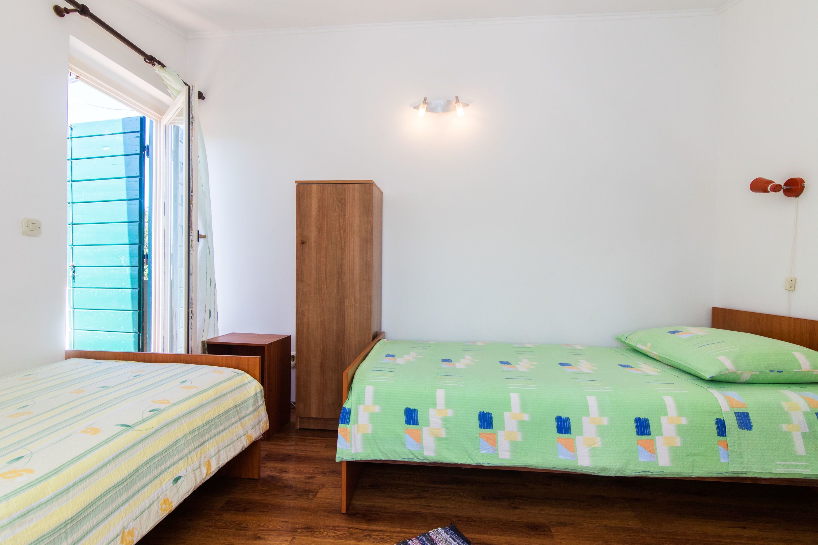 Ein Schlafzimmer mit zwei Betten, einem Schrank und einem kleinen Nachttisch.