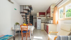 Una cucina compatta con zona pranzo, una scala e un divano.