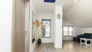 A modern living room with a wooden floor, a sofa, a coffee table, and a large window with blinds. - Apartment Loro (Ploce)