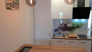 Cozinha moderna com armários brancos, bancada de madeira, pia e duas luminárias pendentes.