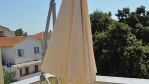 Varanda com um guarda-sol bege e corrimão branco.