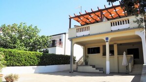 Um edifício de dois andares com entrada coberta e escadaria que dá acesso ao andar superior.