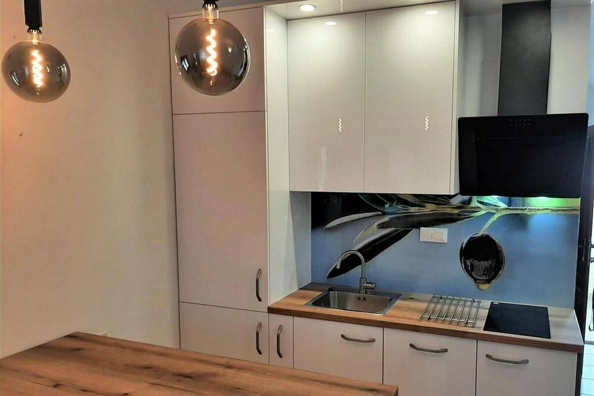 A modern kitchen with white cabinets, a wooden countertop, and two pendant lights.