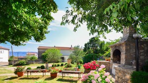 A garden with a stone-built outdoor oven, potted plants, and a bench. - Apartments Zorka (Novi Vinodolski)