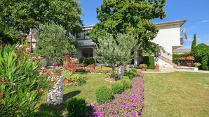 A residential property with a well-maintained garden, a stone pillar, and a staircase leading to a balcony. - Apartments Zorka (Novi Vinodolski)