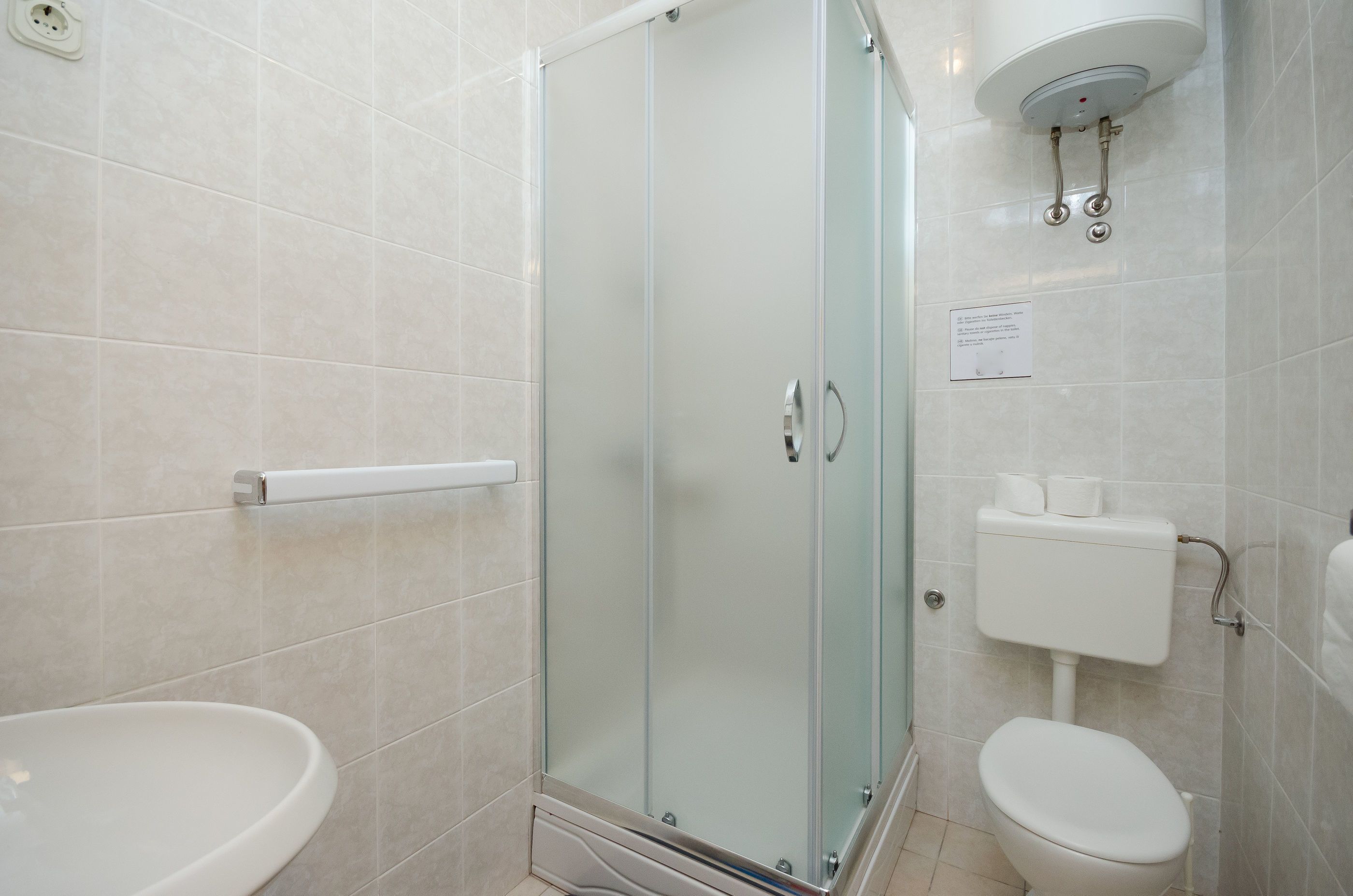 A modern bathroom with a glass-enclosed shower, a white sink, and a toilet.