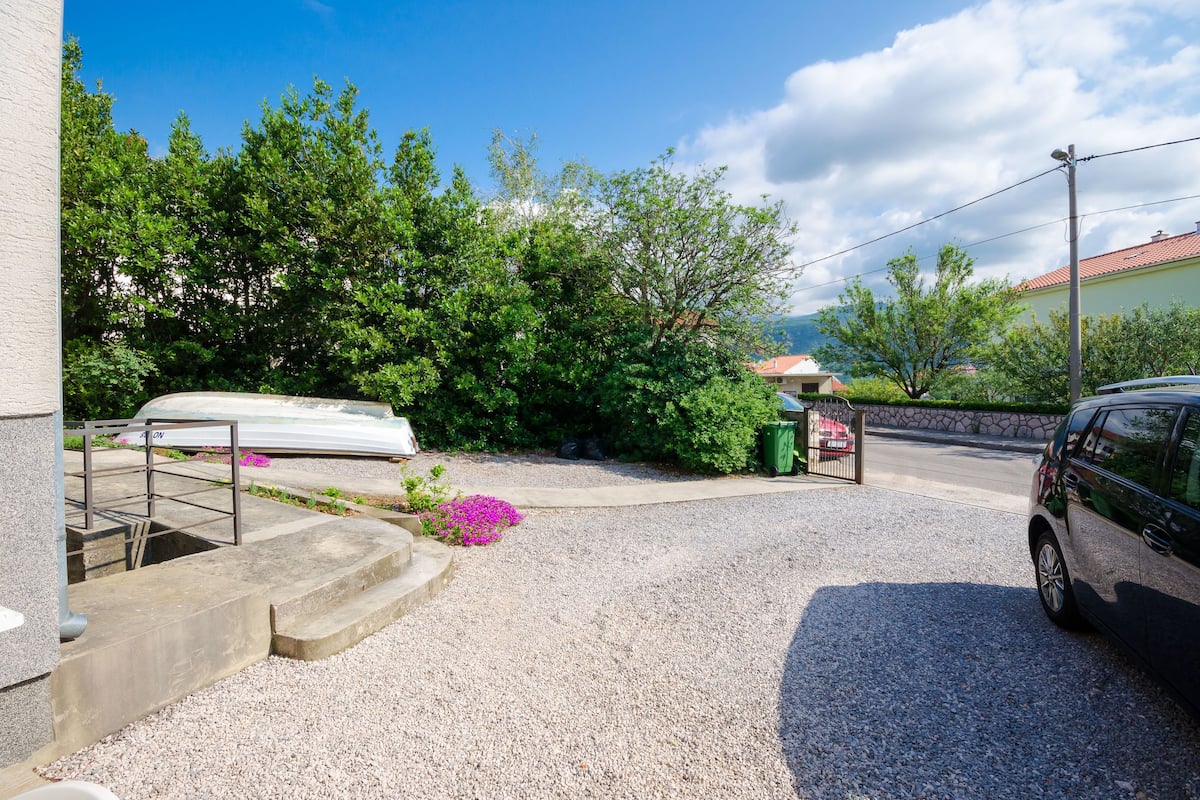 A gravel driveway leading to a house with a car parked on the right.