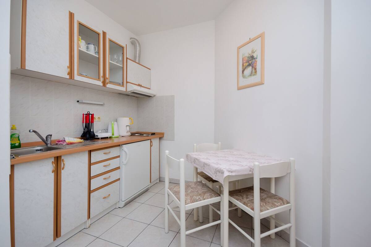 Una piccola cucina con mobili in legno, un lavello e un tavolo con sedie.