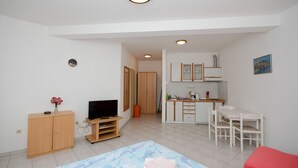 Un espacio habitable compacto con televisor, mueble de madera, kitchenette y comedor.