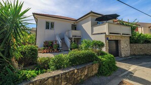A two-story house with a stone wall, a balcony, and a staircase leading to the entrance. - Apartments Toni (Banjol)