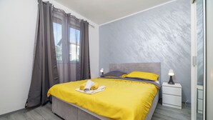 A bedroom with a bed, curtains, a bedside table, and a lamp. - Apartments Toni (Banjol)