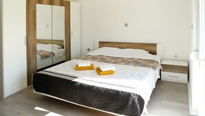 Een slaapkamer met een bed, een kledingkast, een nachtkastje en een spiegel.