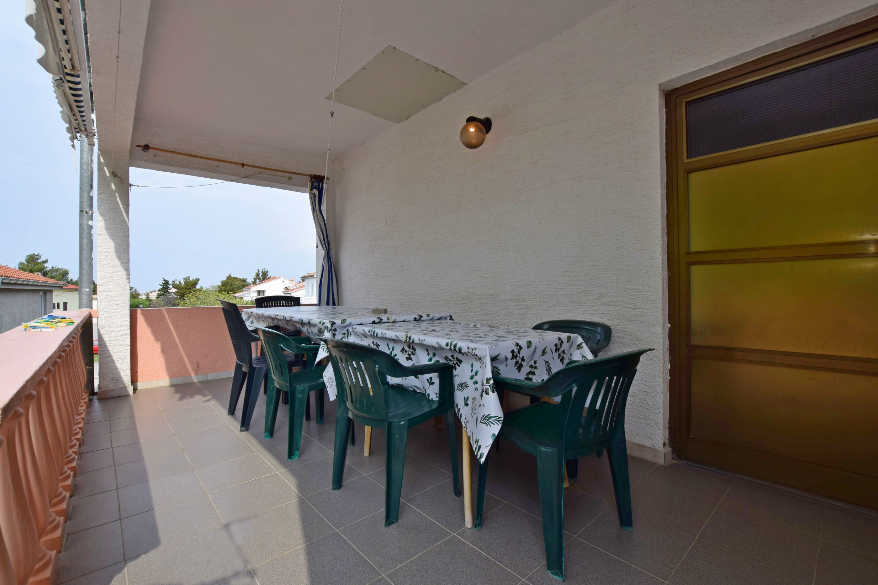 Un espace extérieur abrité, aménagé pour prendre les repas, avec une table et des chaises, une vue sur le ciel et un bâtiment en arrière-plan.