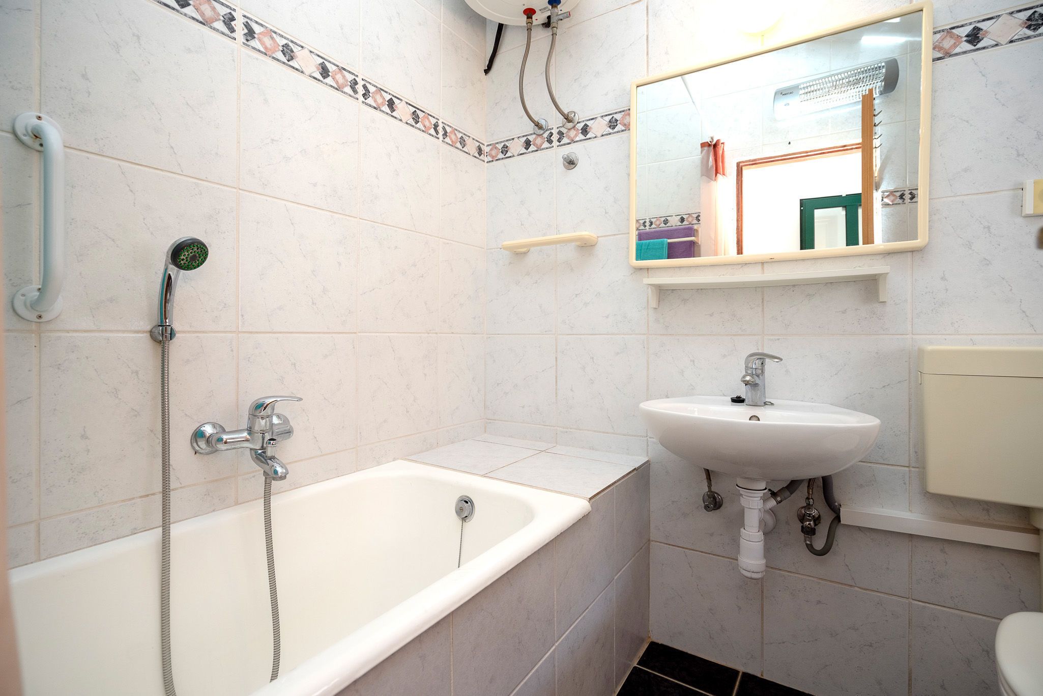 A bathroom with a bathtub, a sink, and a mirror.
