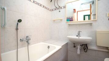 A bathroom with a bathtub, a sink, and a mirror.