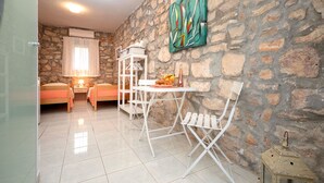 Une pièce chaleureuse avec un mur en pierre, un lit, une table avec des chaises et un luminaire suspendu.