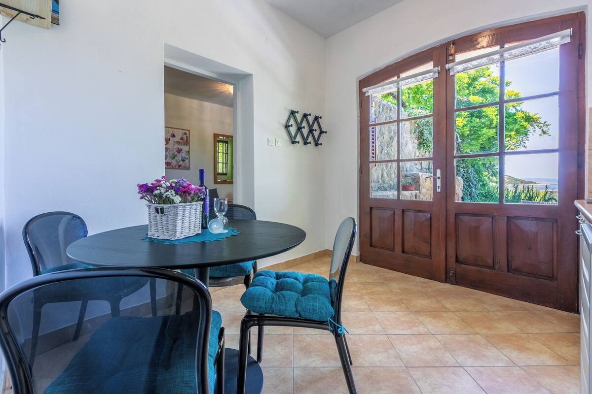 A dining area with a round table, chairs, and a basket of flowers.