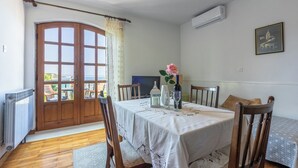 Un comedor con una mesa dispuesta para cuatro, una puerta de madera con paneles de vidrio, y una vista a través de la puerta.
