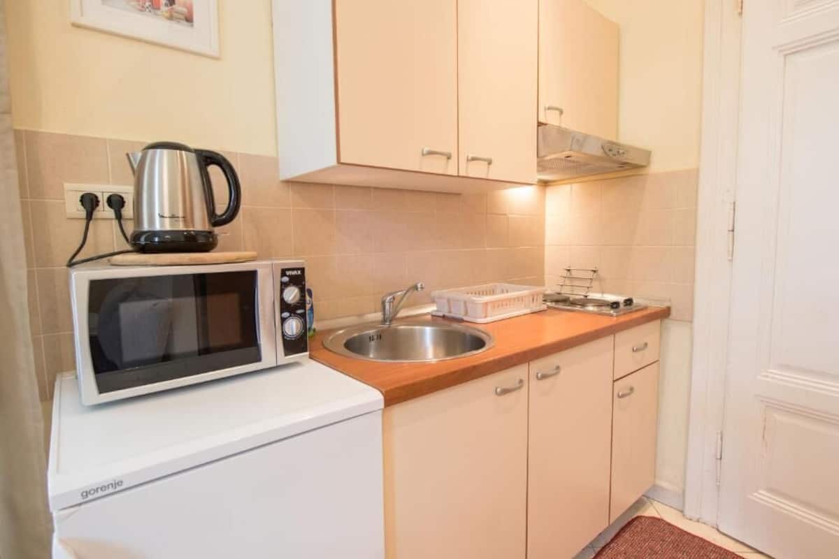 A compact kitchen with a microwave, kettle, and sink.