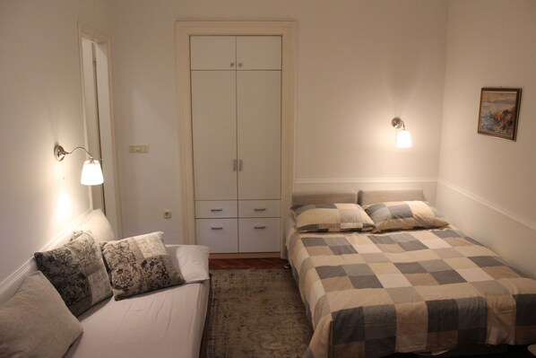 A bedroom with a bed, a wardrobe, a nightstand, and a wall-mounted lamp. - Apartments Rezine (Lovran)