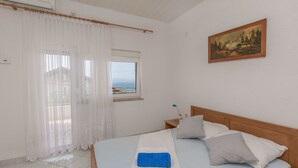 Ein Schlafzimmer mit Bett, Vorhängen, einem Gemälde und einem Fenster mit Blick.