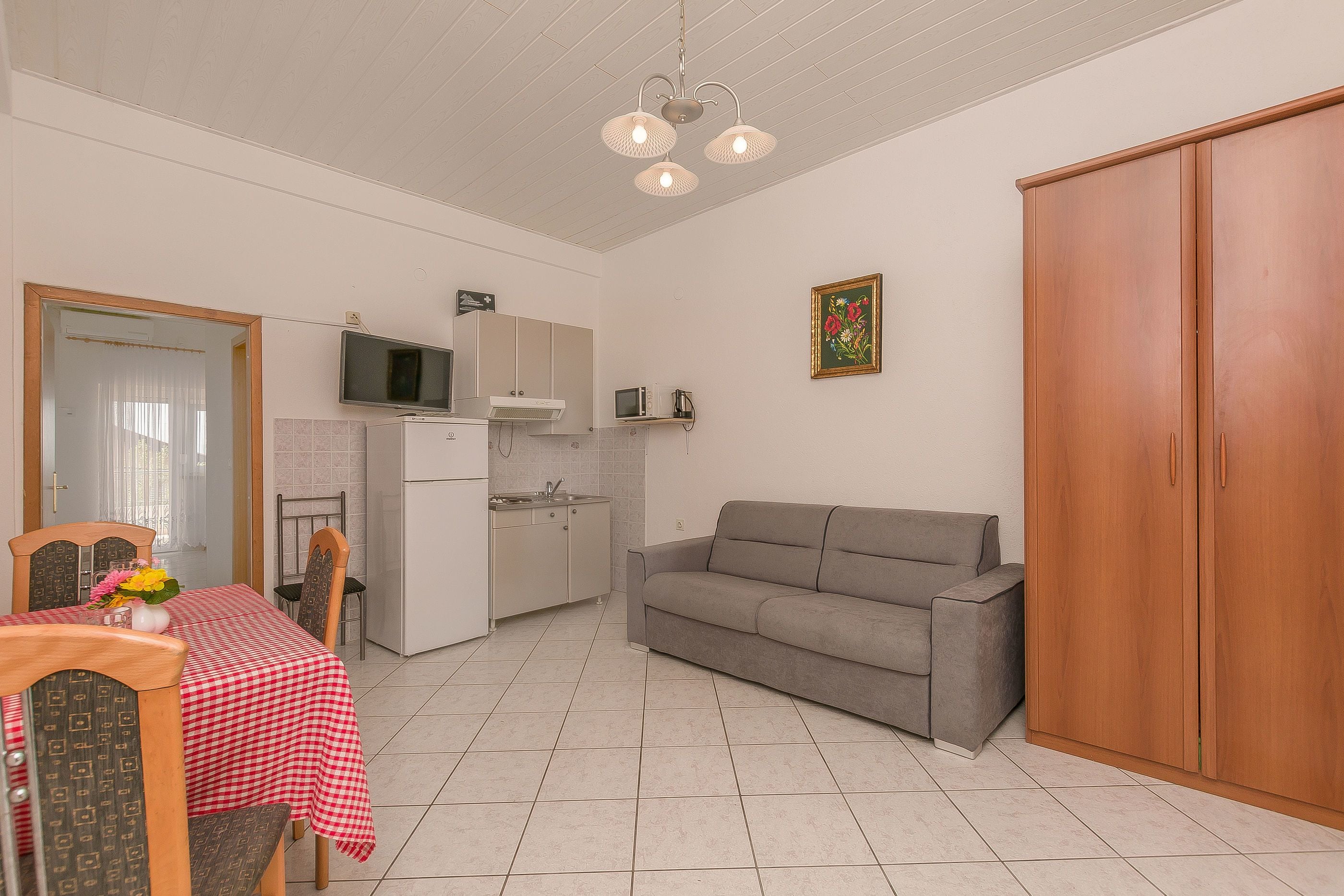 Un espace de vie compact comprenant un coin cuisine, une table à manger avec des chaises, un canapé et une armoire.