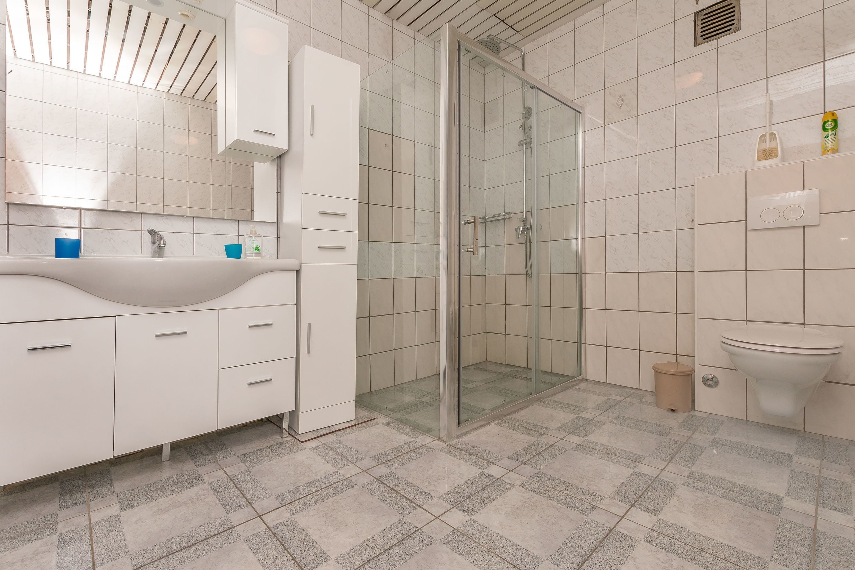 A modern bathroom with a glass-enclosed shower, a white sink with a mirror above, and a toilet.