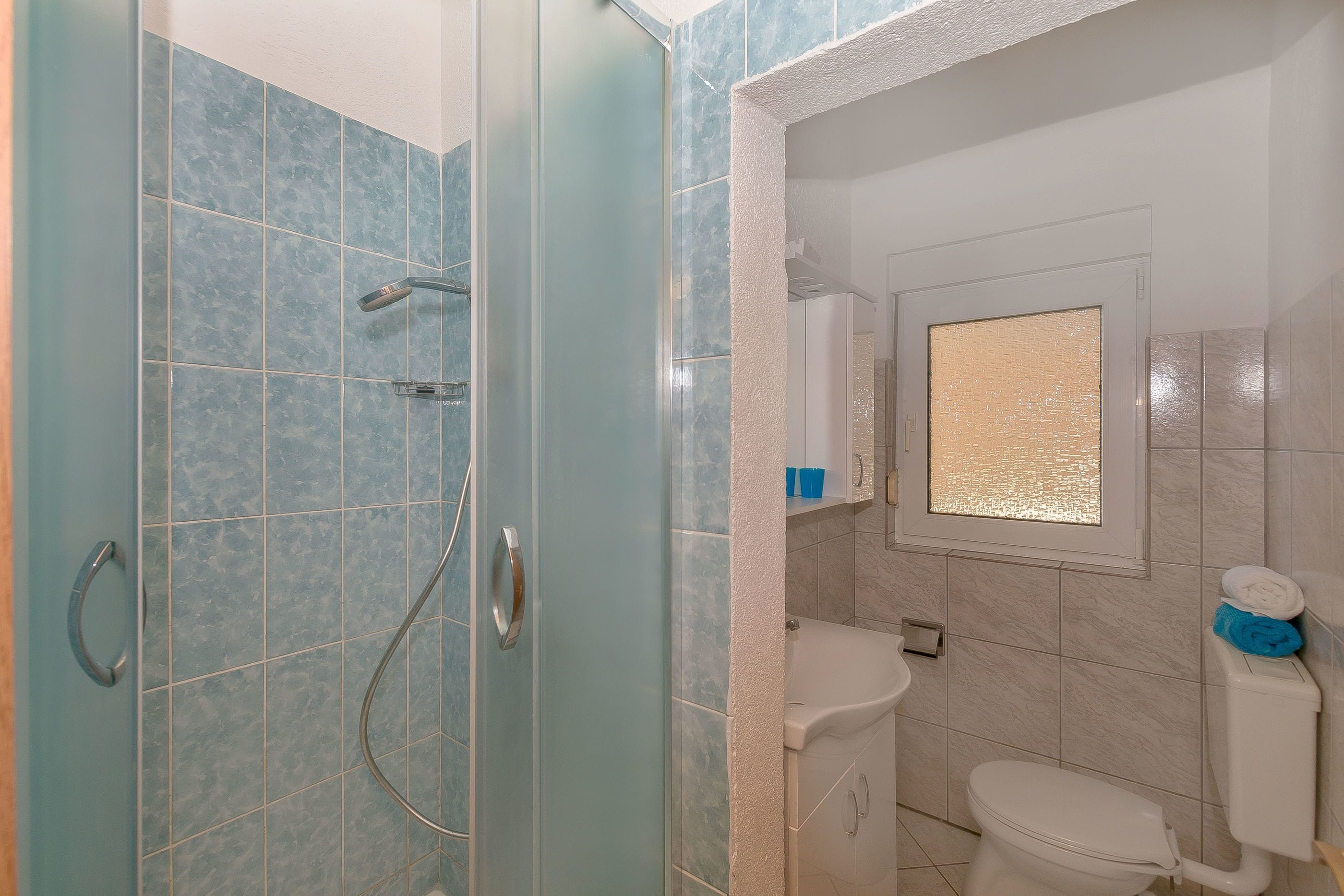 Une salle de bain avec douche, toilettes et lavabo.