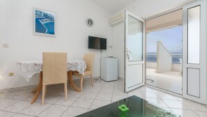Ein Zimmer mit Esstisch, Stühlen, einem Fernseher und einem Balkon mit Blick.