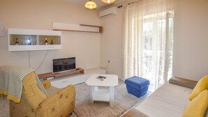 Una sala de estar con sofá, una mesa de centro, televisor y un mueble con botellas y vasos.