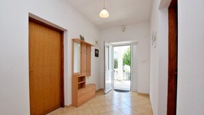 Un pasillo con una puerta y un armario de madera, y suelo de baldosas.