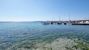 Un puerto deportivo con barcos amarrados, agua cristalina y un muelle que se adentra en el agua.