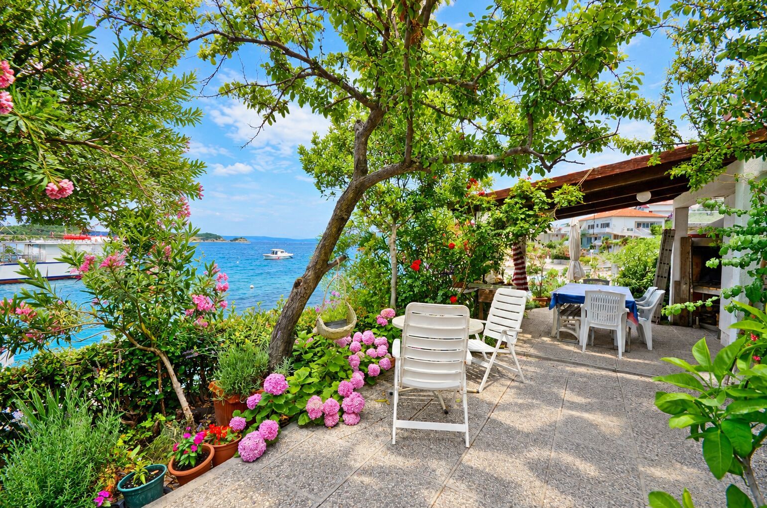 A patio with outdoor seating, a view of the sea, and potted plants.