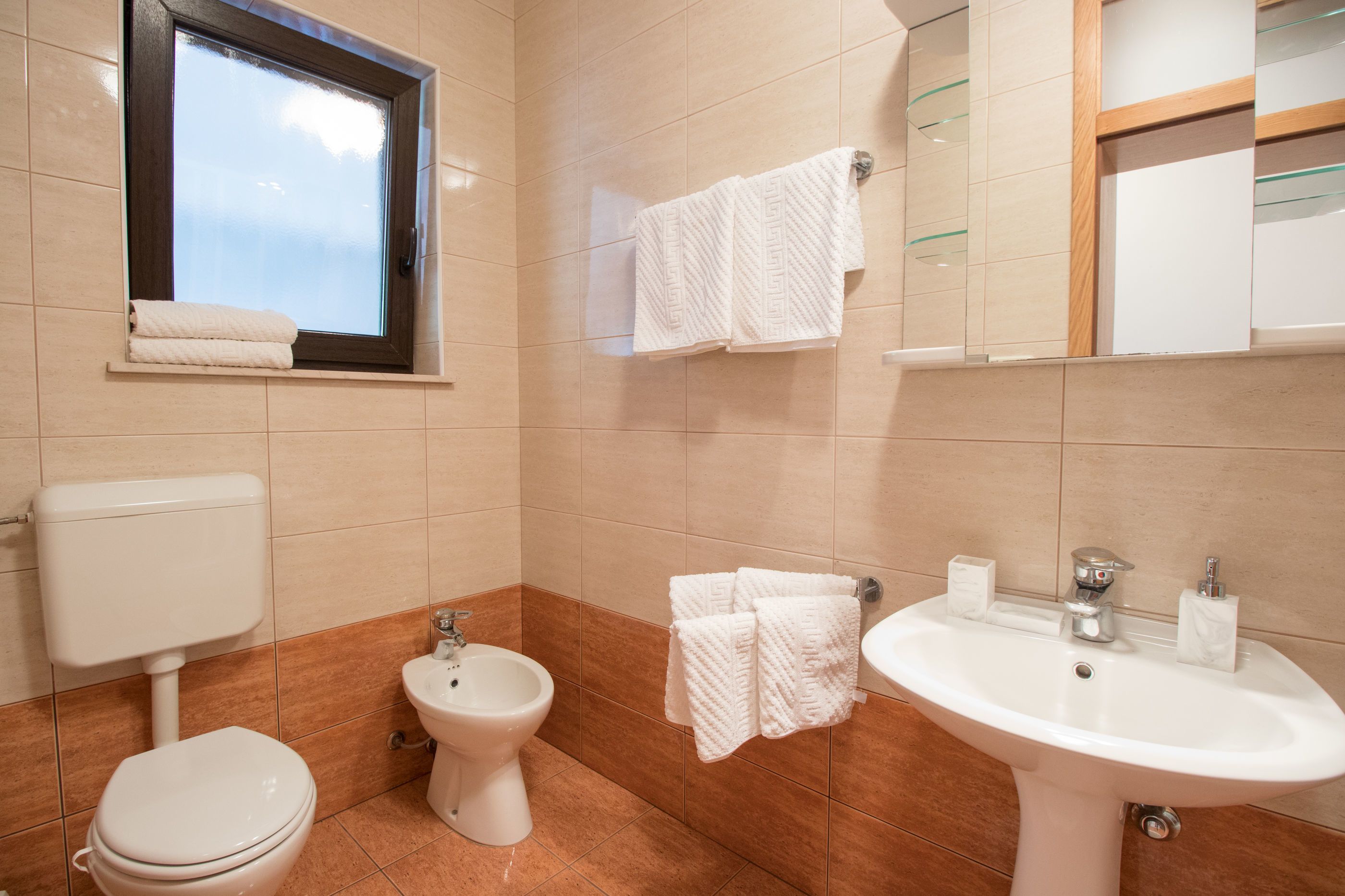 A bathroom with a toilet, bidet, and sink.